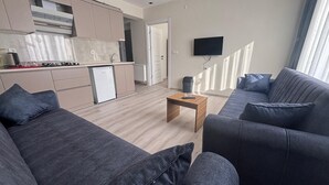 Een moderne woonkamer met een grijze bank, een salontafel en een aan de muur bevestigde televisie.