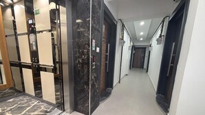 Een moderne hal met een marmeren vloer, een lift en glazen deuren.