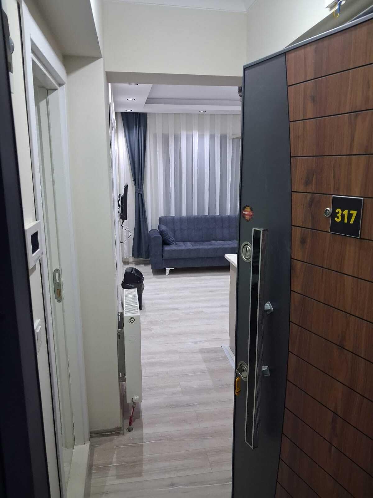 A hotel room with a wooden wardrobe, a grey sofa, and a curtain.
