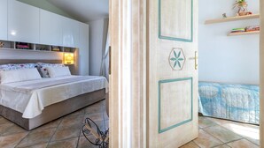Un dormitorio con cama, armario, puerta con panel decorativo y estante con libros y una planta.