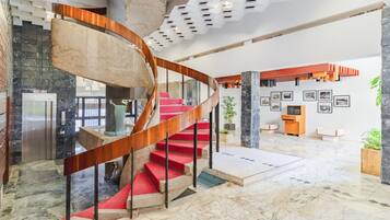 A modern interior with a spiral staircase, marble flooring, and a wall with framed pictures.