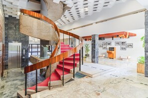Ein modernes Interieur mit einer Wendeltreppe, Marmorböden und einer Wand mit gerahmten Bildern.