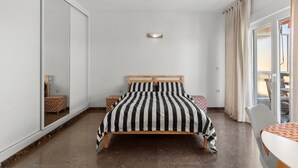 Ein Schlafzimmer mit einem Bett, einem Nachttisch, einem Spiegel und einer Schiebetür.