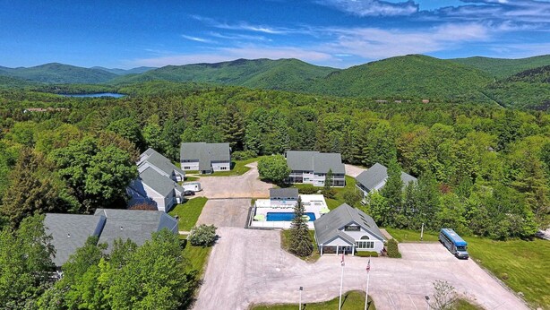 An aerial view of a residential area with houses, a swimming pool, and a parking lot. - Killington Center Renovated Studio with Kitchenette on Bus Route and Discounted Ski Rentals. (Killington)