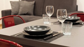 Una mesa de comedor servida con un tazón negro, dos copas de vino y dos vasos de agua.