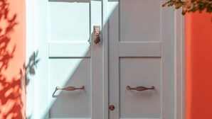 A white double door with a handle, set against a red wall. - Villa Malia, Eco-Chic Villa with SeaViews (Syros)