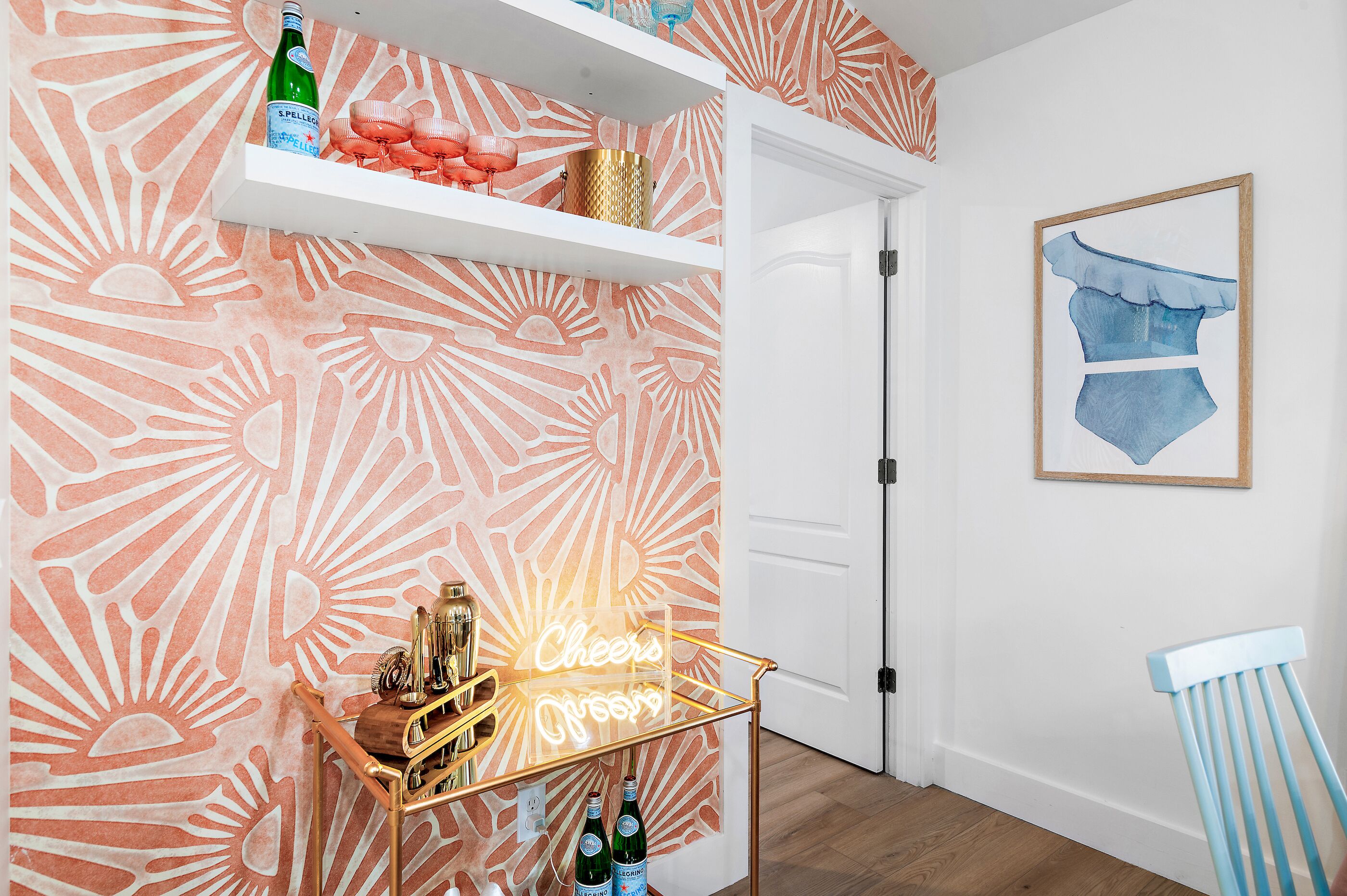 Ein Zimmer mit einem gemusterten Wand, einer Neonreklame, einem Regal mit Flaschen und einem gerahmten Bild.