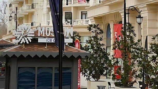 Een meerlaags gebouw met balkons, een klok en straatverlichting.