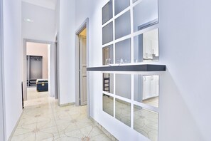 A hallway with a patterned floor, a door leading to a room, and a wall-mounted shelf with a glass bowl. - GuestHost - This bright, recently renovated apartment is located in a charming 18th-century building, in a quiet and secluded location despite being in a lively and central area just steps from Via Foria and Via Cesare Rosaroll. The Cavour Metro Line 2,  (Naples)