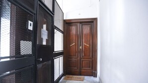 A hallway with a black metal gate, a wooden double door, and a welcome mat. - GuestHost - This bright, recently renovated apartment is located in a charming 18th-century building, in a quiet and secluded location despite being in a lively and central area just steps from Via Foria and Via Cesare Rosaroll. The Cavour Metro Line 2,  (Naples)