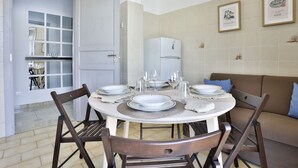 A dining area with a round table set for four, a white refrigerator, and a sofa with cushions. - GuestHost - This bright, recently renovated apartment is located in a charming 18th-century building, in a quiet and secluded location despite being in a lively and central area just steps from Via Foria and Via Cesare Rosaroll. The Cavour Metro Line 2,  (Naples)