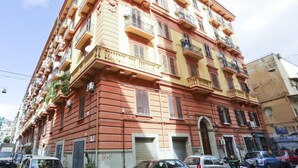 A multi-story building with balconies, a ground floor entrance, and parked cars. - GuestHost - This bright, recently renovated apartment is located in a charming 18th-century building, in a quiet and secluded location despite being in a lively and central area just steps from Via Foria and Via Cesare Rosaroll. The Cavour Metro Line 2,  (Naples)