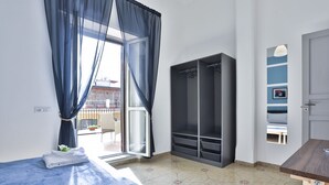A bedroom with a bed, a wardrobe, a desk, and a view of the outside. - GuestHost - This bright, recently renovated apartment is located in a charming 18th-century building, in a quiet and secluded location despite being in a lively and central area just steps from Via Foria and Via Cesare Rosaroll. The Cavour Metro Line 2,  (Naples)