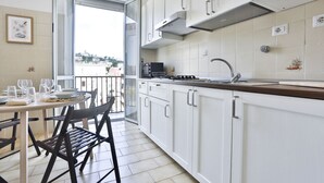 A modern kitchen with white cabinets, a stainless steel range hood, and a dining area with a table set for four. - GuestHost - This bright, recently renovated apartment is located in a charming 18th-century building, in a quiet and secluded location despite being in a lively and central area just steps from Via Foria and Via Cesare Rosaroll. The Cavour Metro Line 2,  (Naples)