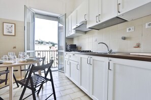 Une cuisine moderne avec des armoires blanches, une hotte en acier inoxydable et un coin repas avec une table dressée pour quatre personnes.