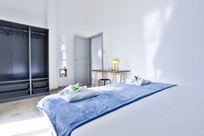 A hotel room with a bed, a desk, a chair, a wardrobe, and a mirror. - GuestHost - This bright, recently renovated apartment is located in a charming 18th-century building, in a quiet and secluded location despite being in a lively and central area just steps from Via Foria and Via Cesare Rosaroll. The Cavour Metro Line 2,  (Naples)