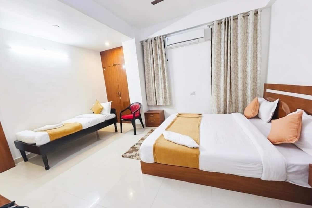 A hotel room with a single bed, a sofa bed, a desk, and a chair.