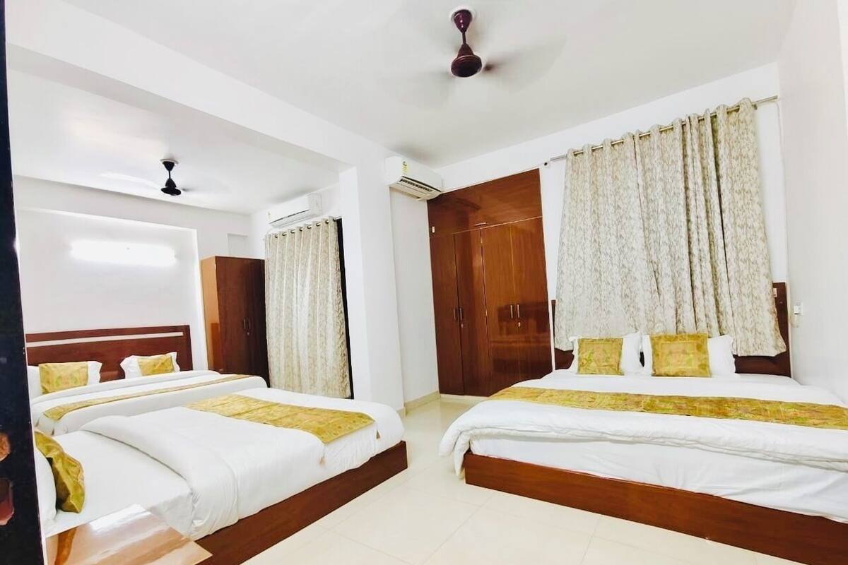 A hotel room with two single beds, a wardrobe, a ceiling fan, and a window with curtains.
