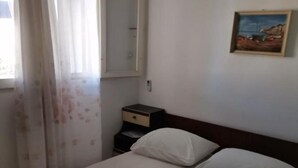 Una habitación de hotel con una cama, una mesita de noche, un cuadro y un equipo de aire acondicionado.