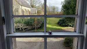 A window with a view of a garden, a gravel path, and a building with a stone facade. - The Coach House- Canonbie (Canonbie)