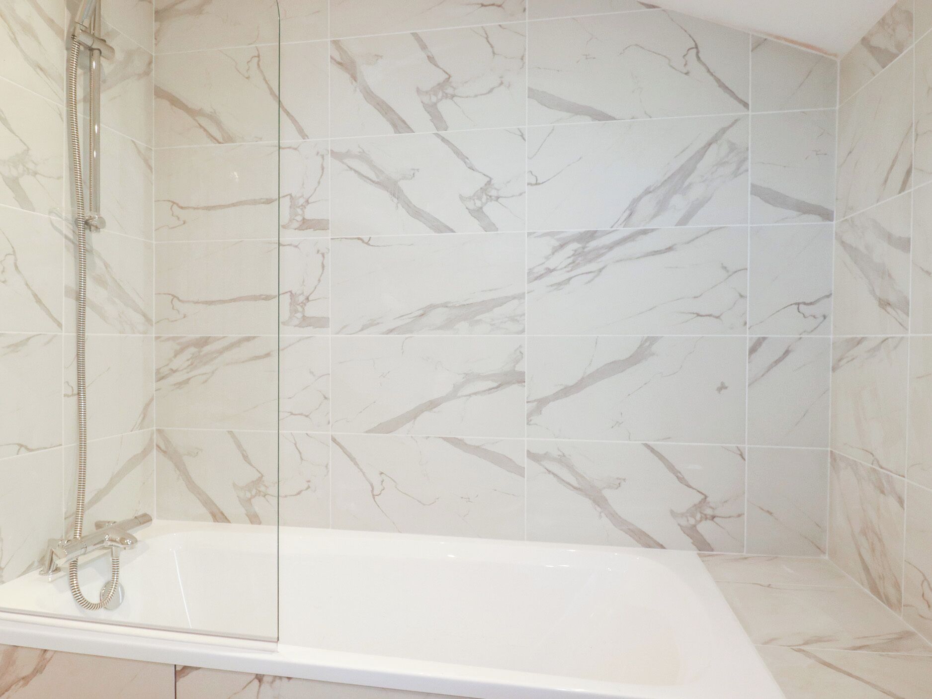 A bathroom with a bathtub, a shower, and marble tiles.