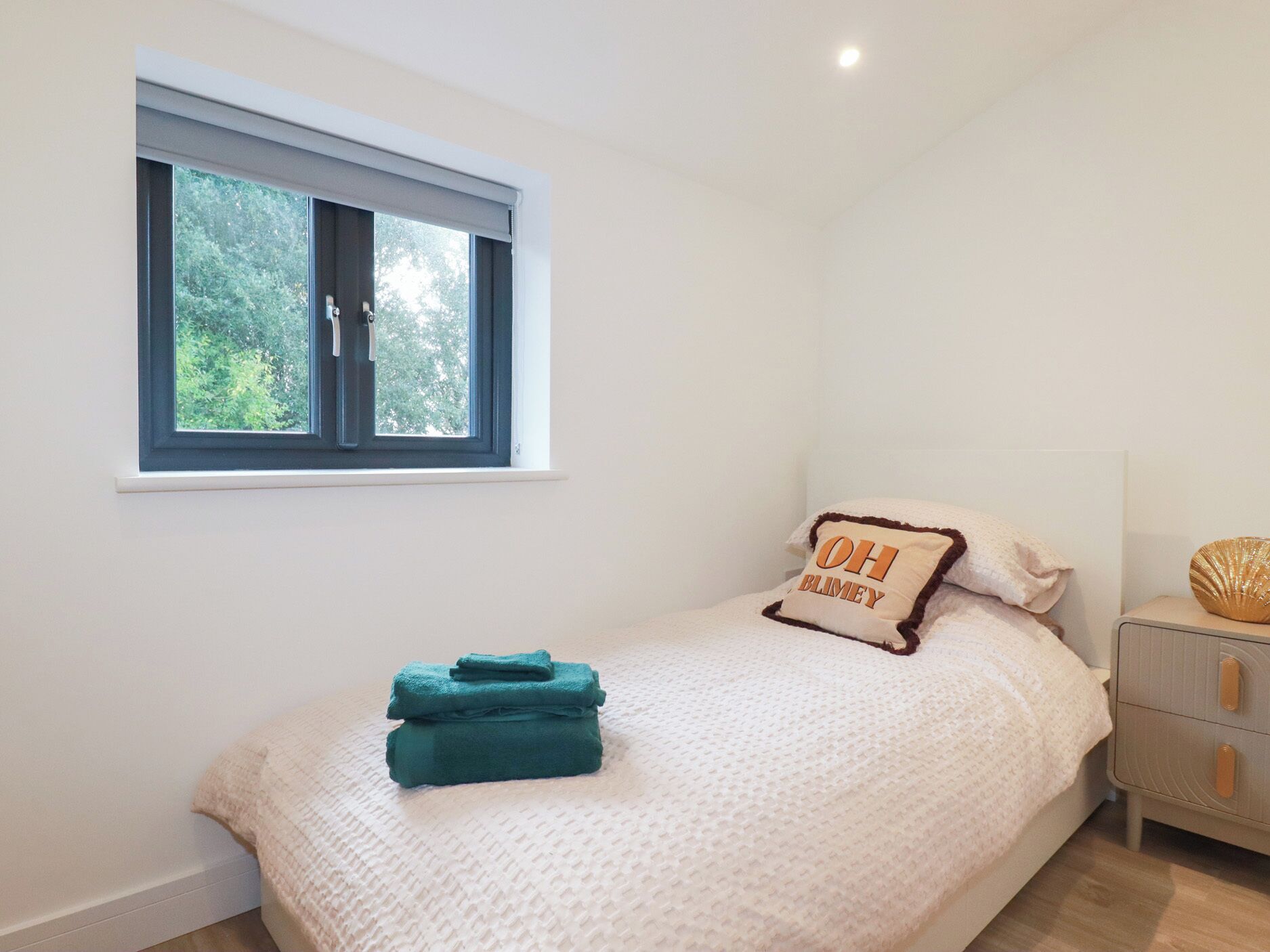 A bedroom with a bed, a window, a bedside table, and a nightstand.