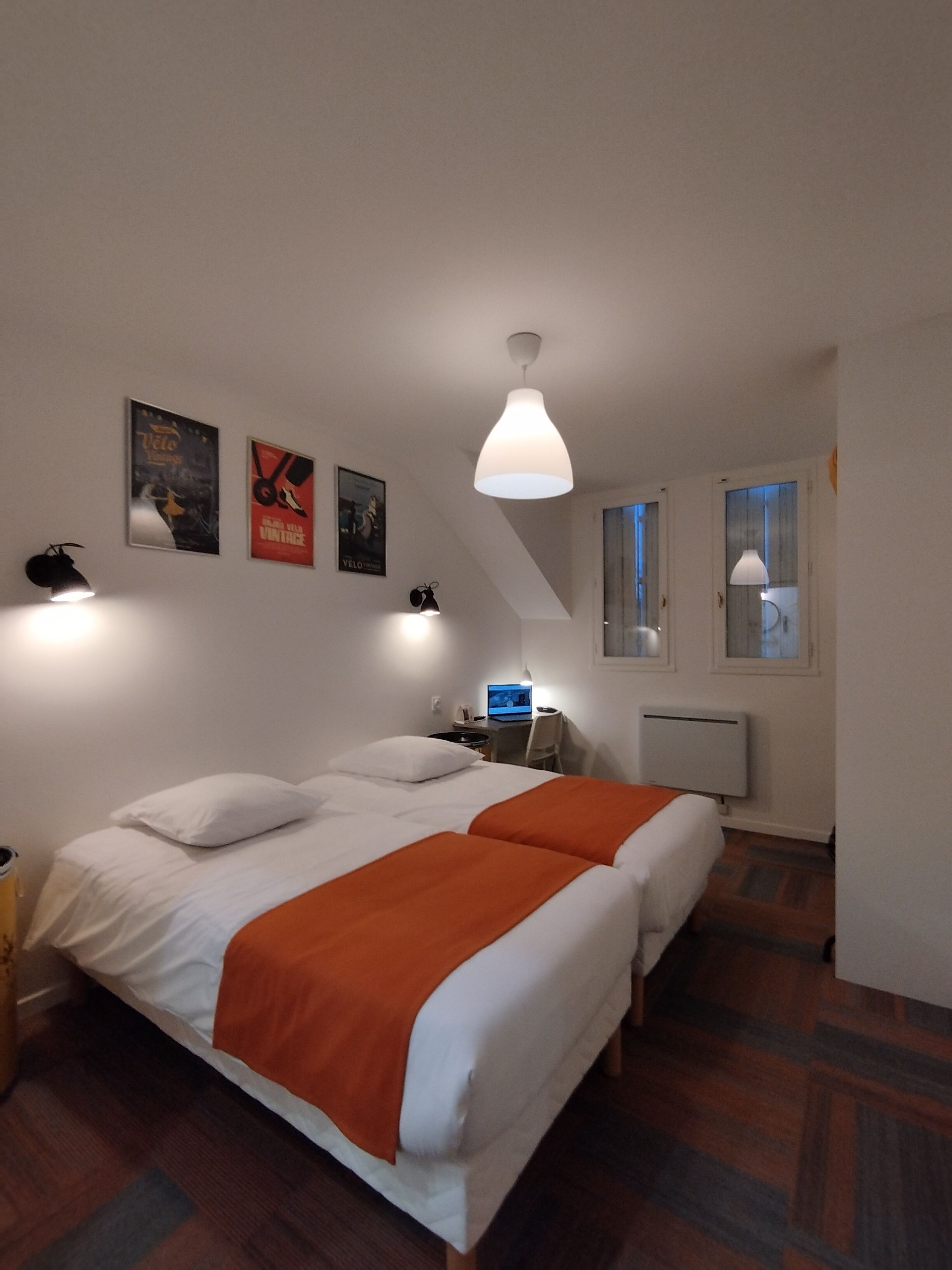 Un dormitorio con dos camas, un escritorio, una silla y un radiador.