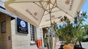 A table with a bottle of sauce, a glass of red wine, and a glass of white wine, with a wicker basket containing bread. - The Originals Access Hotel Le Canter (Saumur)