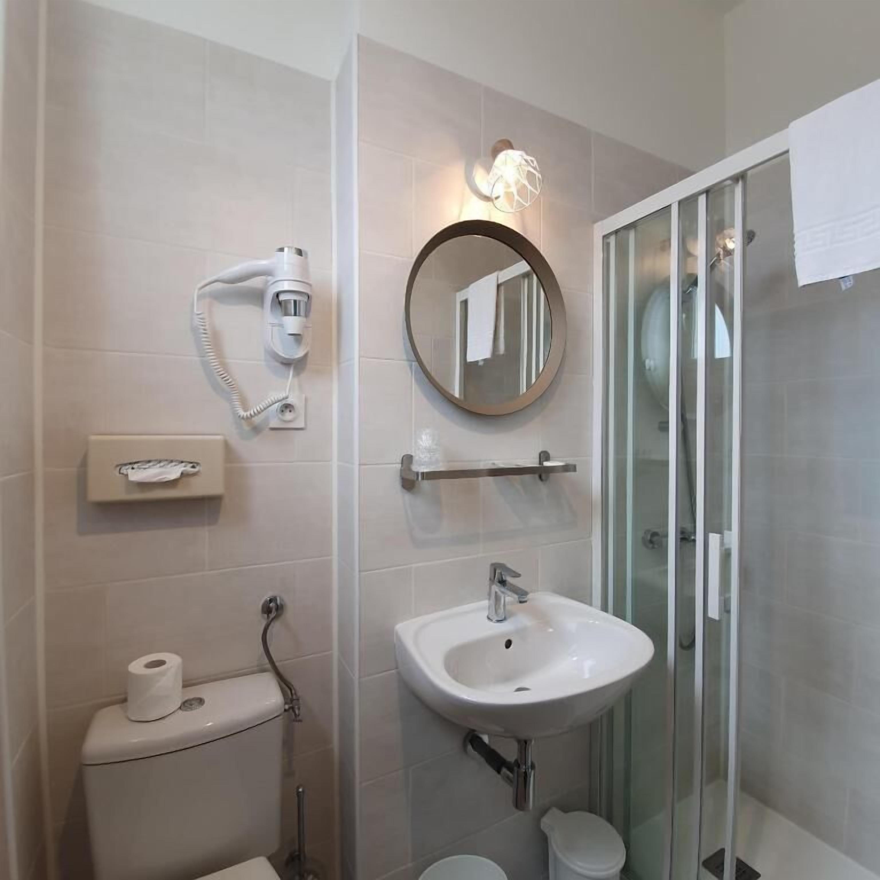 A bathroom with a toilet, sink, and glass shower enclosure.