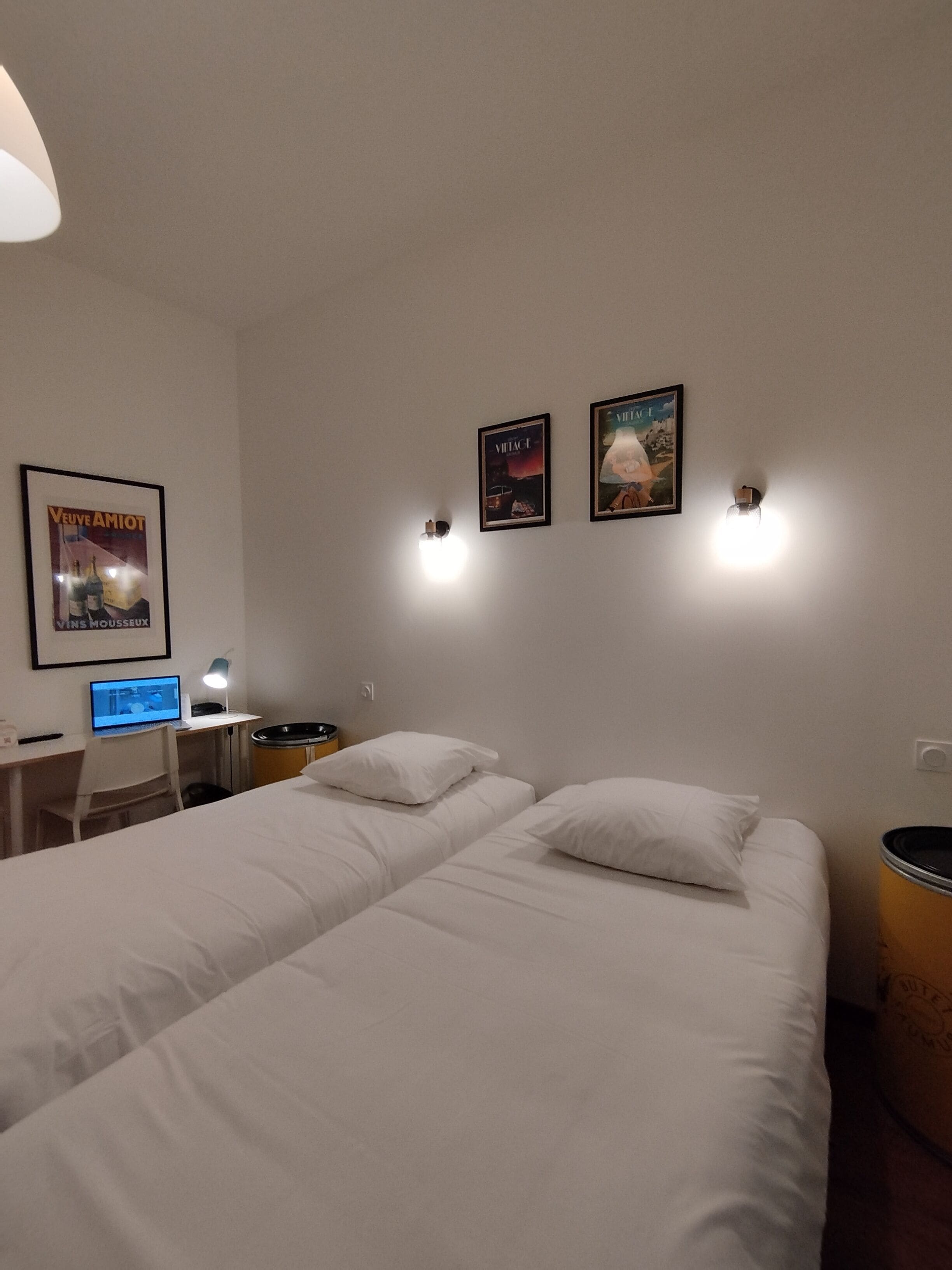 Una habitación de hotel con una cama grande, un escritorio con computadora y dos luces fijadas a la pared.