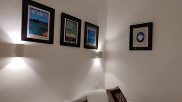 A hotel room with a bed, two pillows, and three framed pictures on the wall.