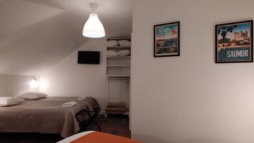 Een hotelkamer met twee bedden, een kast en twee ingelijste foto’s aan de muur.