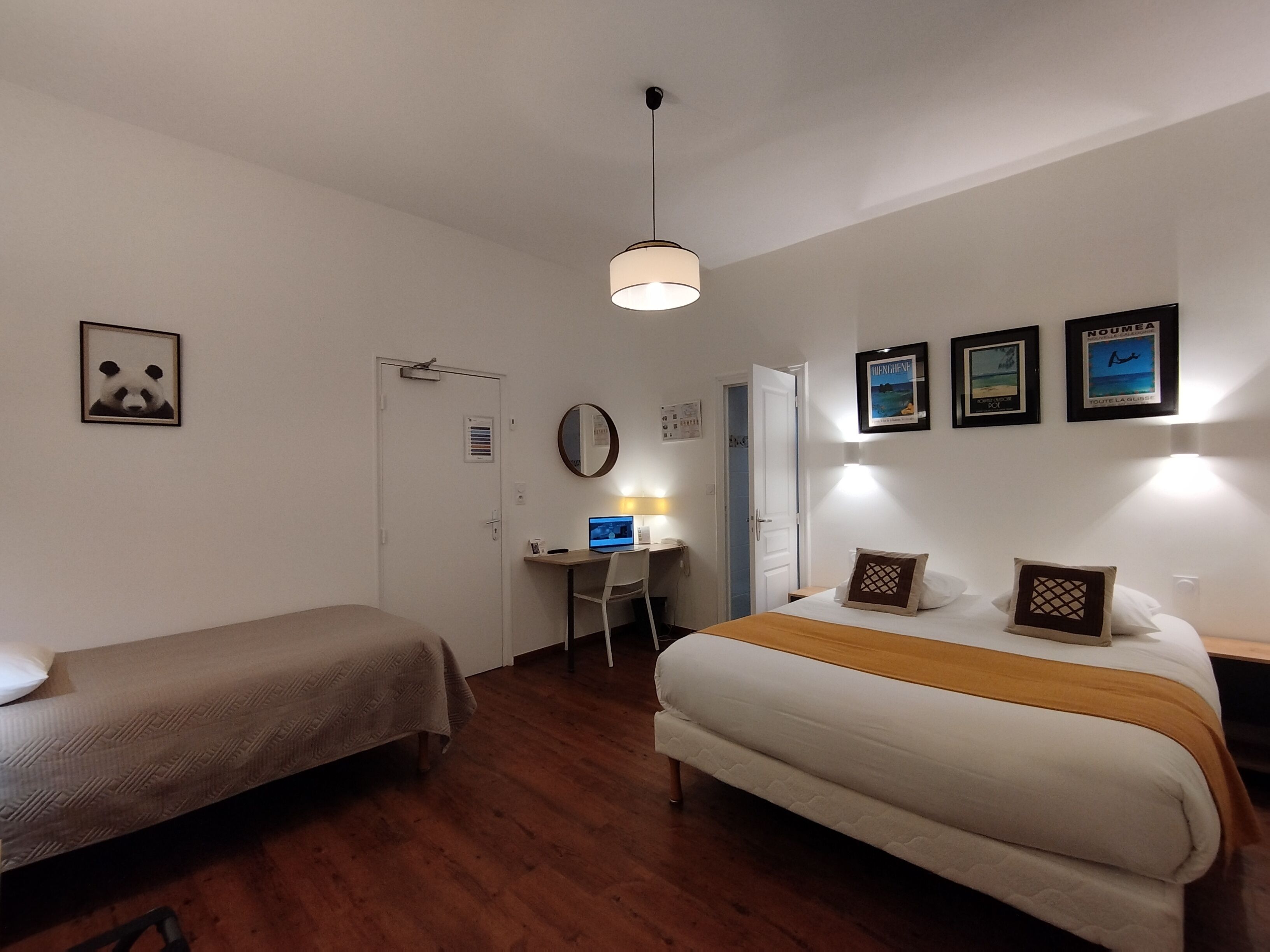 Habitación de hotel con dos camas individuales, un escritorio con silla, una computadora y una mesita.