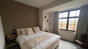 A modern bedroom with a large bed, a nightstand, a chair, and a window with curtains. - Hidden Secret of Nature in the middle of Old Flanders, in nature. (Maaseik)
