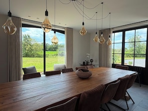 A dining area with a wooden table, multiple chairs, and hanging light fixtures.