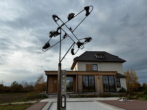 A modern house with a large glass window and a metal sculpture in front. - Hidden Secret of Nature in the middle of Old Flanders, in nature. (Maaseik)