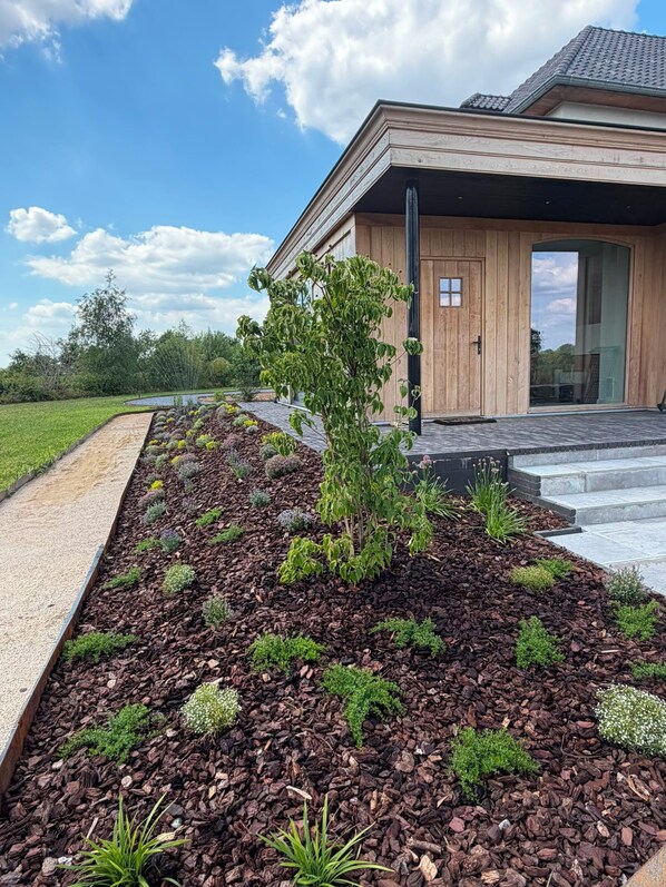 A modern house with a landscaped garden featuring mulch and various plants.