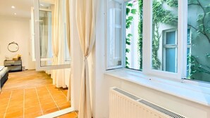 Una habitación con un ventanal grande, un radiador y suelo de baldosas.