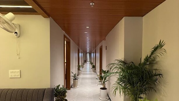 A hotel corridor with a marble floor, wooden ceiling, and potted plants along the walls. - Hotel Blesskey (Jaipur)