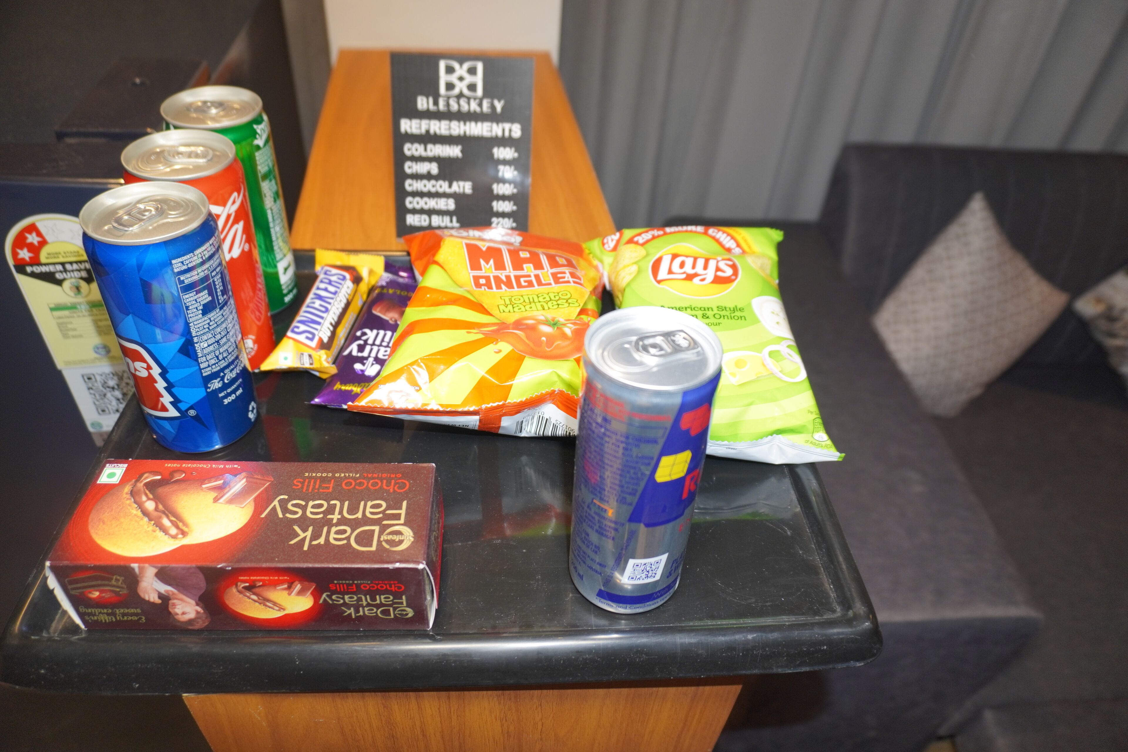 A snack and refreshment table with various items including cans, chips, and a box of chocolate.