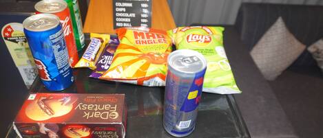 A snack and refreshment table with various items including cans, chips, and a box of chocolate.