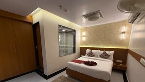 A modern bedroom with a large bed, a wardrobe, a window, and a ceiling fan. - Hotel Blesskey (Jaipur)
