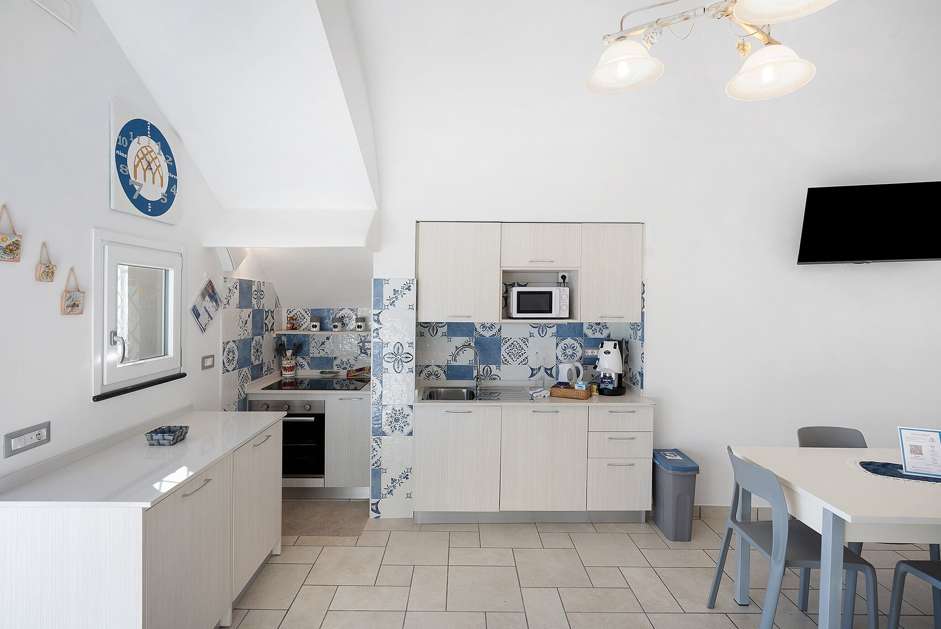 A modern kitchen with white cabinets, a microwave, and a dining area with a table and chairs.