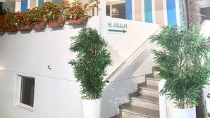 A modern building with a staircase, potted plants, and a sign reading 'H. Amalfi'.