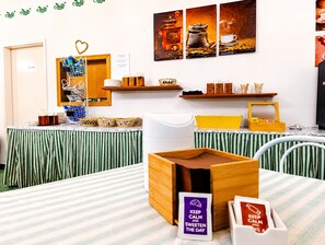 Ein Zimmer mit gestreiften, grün-weißen Vorhängen, einer Kaffeestation mit Körben und Tassen sowie einer Wand mit gerahmten Kaffeebildern.