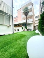 Un cortile con un prato curato, una palma e un oggetto sferico bianco.