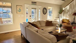 A living room with a beige sofa, a coffee table, and a staircase with a railing. - “Just Lake Home” Wonderful 3bdrm 2bath lake front,boat ramp, dock, pet friendly (Jackson's Gap)