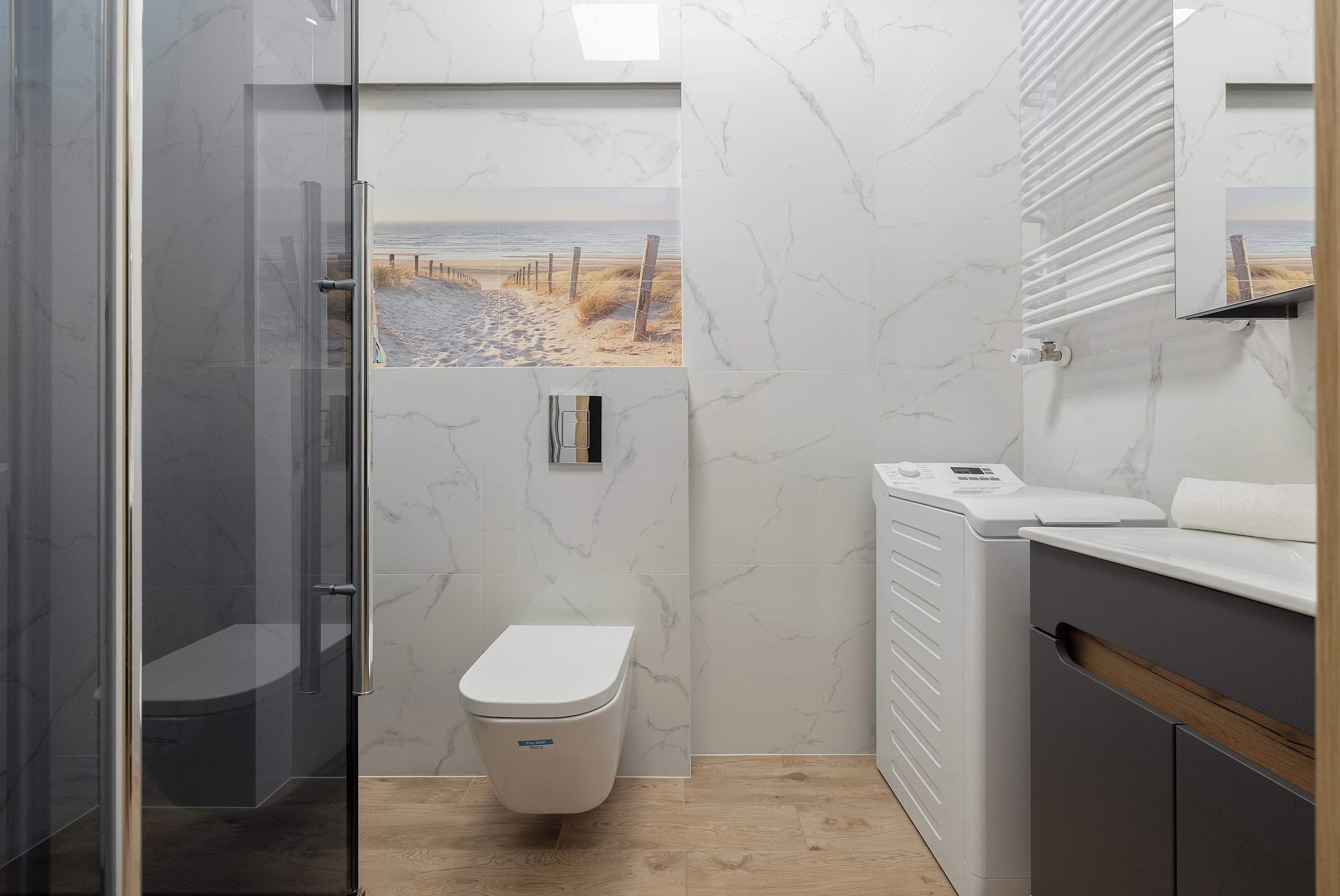 Ein Badezimmer mit Toilette, einer Duschkabine aus Glas und einem Waschbecken mit Spiegel.