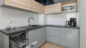 Uma cozinha moderna com lava-louças, micro-ondas e máquina de café no balcão.
