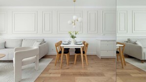 Een moderne eetruimte met een witte tafel, vier houten stoelen en een hanglamp.
